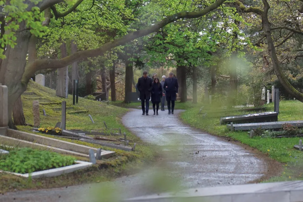 Een familie loopt over een slingerend pad tussen oude graven en hoge bomen op begraafplaats Westerveld