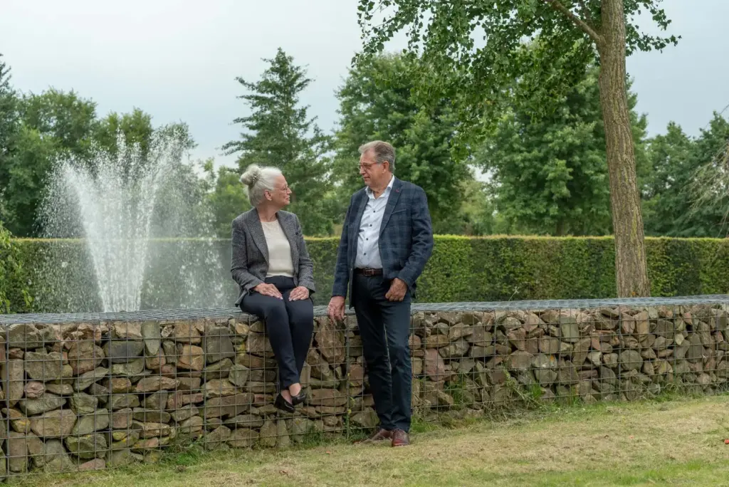 Martin Uitendaal en Sonja Raijmakers bij een stenen muur met een fontein erachter