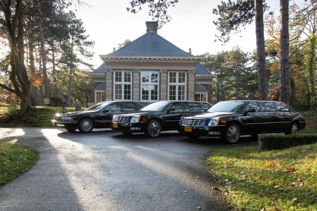 Rouwauto's van Uitvaartverzorging Uitendaal op de oprijlaan van een begraafplaats