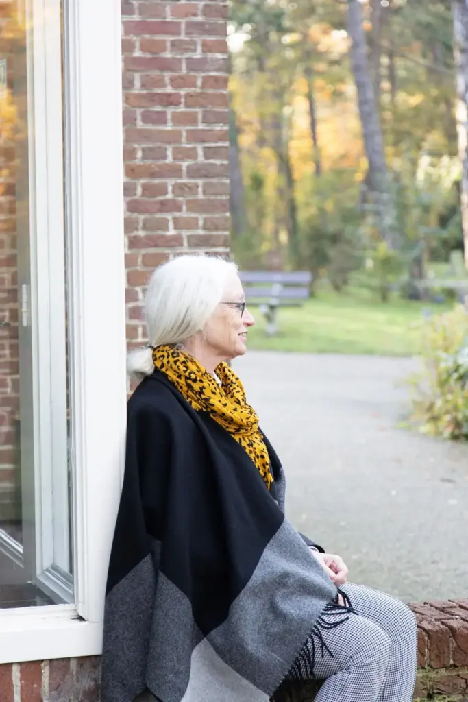 Sonja Raijmakers zit bij een raam en kijkt naar buiten