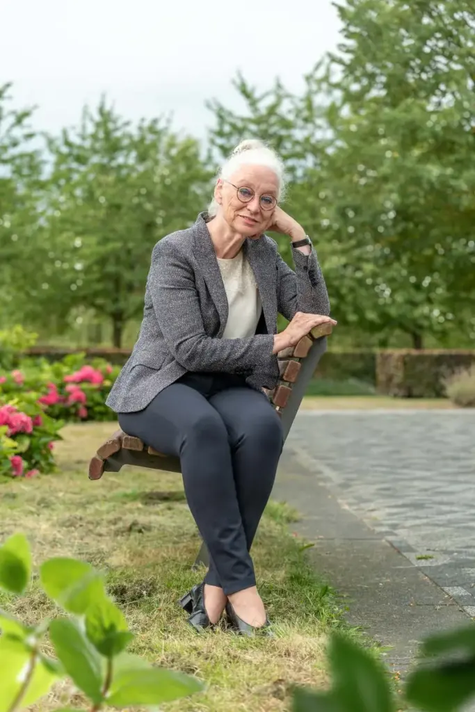 Sonja Raijmakers zit op een bankje in een tuin